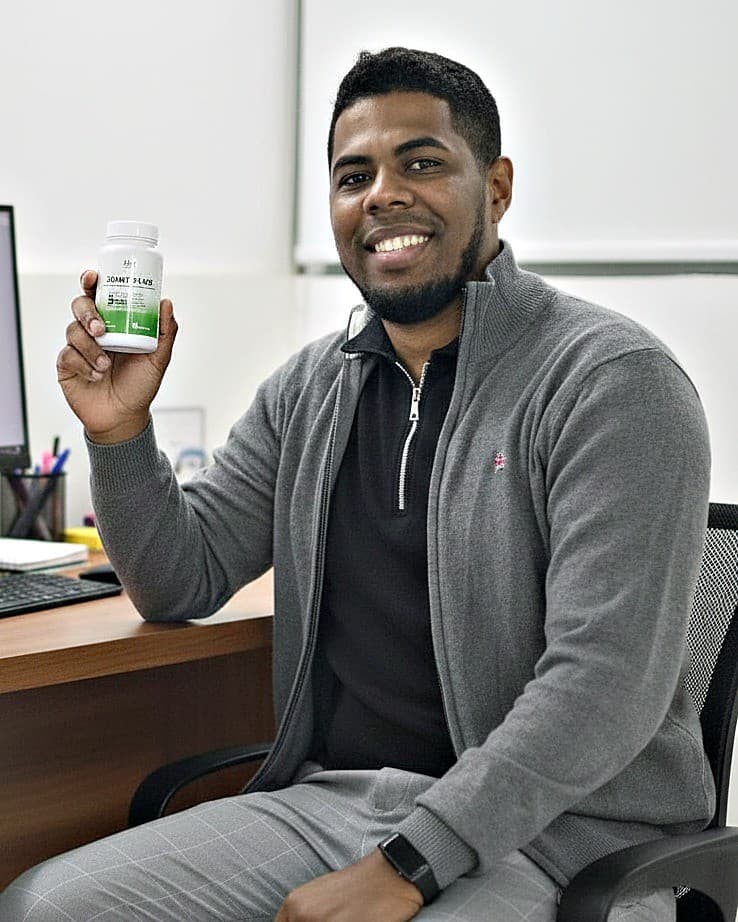 Eldwin Olivo, fundador de Aloy Natural, sentado en su oficina sosteniendo un envase de Joint Plus